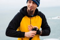 Homem adulto barbudo enrolando bandagem em torno da mão enquanto está contra o mar — Fotografia de Stock