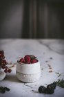 Свіжі літні ягоди в чашках на поверхні білого мармуру — стокове фото