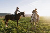 Чоловік і жінка катаються на конях проти заходу сонця небо на ранчо — стокове фото