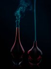 Bottiglie di vetro che emettono fumo su sfondo nero — Foto stock