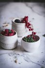 Bacche fresche estive in tazze su superficie di marmo bianco — Foto stock