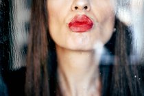 Primer plano de labios rojos femeninos besar vidrio transparente limpio apasionadamente - foto de stock