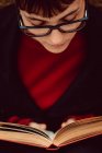 Nahaufnahme einer jungen eleganten Frau mit Brille beim Lesen eines Buches — Stockfoto