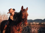 Mulher montando cavalo contra o pôr do sol céu no rancho — Fotografia de Stock