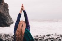 Молода жінка з посиленими руками стоїть на морському узбережжі з галькою в розпалі — стокове фото