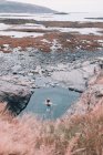 Donna che riposa in acqua vicino a scogliera sulla costa asciutta tra le pietre — Foto stock