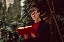 Junge attraktive elegante Frau mit Brille liest Buch im Stadtgarten — Stockfoto
