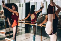 Jovens bailarinas flexíveis treinando em estúdio ensolarado e alongamento músculos. — Fotografia de Stock