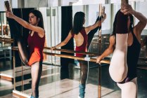 Young flexible ballerinas training in sunny studio and stretching muscles. — Stock Photo