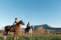 Hombre y mujer montando caballos en el rancho - foto de stock