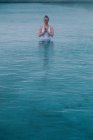 Mujer joven meditando en el agua de la piscina grande - foto de stock