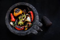 Délicieux légumes rôtis au mortier sur fond noir — Photo de stock