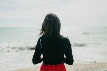 Вид ззаду на брюнетку, захоплюючий вид на спокійне море, стоячи на сонячному пляжі — стокове фото