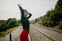 Pretty young woman with closed eyes in stylish outfit posing on blurred background of rails — Stock Photo