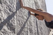 Брюнетка жінка спирається на стіну після тренування в сонячний день — стокове фото