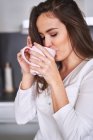 Young woman drinking from mug in modern kitchen at home — Stock Photo