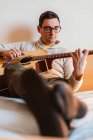 Hombre tocando la guitarra en la cama en casa - foto de stock