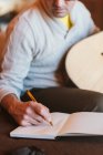 Close-up of musician with guitar writing in notebook — Stock Photo
