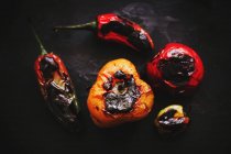 Close-up of roasted vegetables scattered on black background — Stock Photo