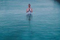Junge Frau meditiert im Wasser eines großen Pools — Stockfoto