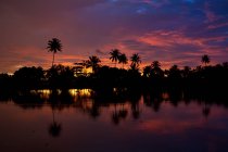 Amazing cloudy sundown sky over silhouettes of tropical palms and calm sea water in majestic India — Stock Photo