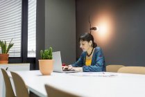Бізнес-леді працює на ноутбуці, сидячи за столом в офісі — стокове фото