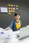 Усміхнена бізнес-леді дає папери з графіками, сидячи за столом в сучасному офісі — стокове фото