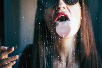 Attraktive Frau mit rotem Lippenstift leckt Flüssigkeitstropfen aus transparentem Glas — Stockfoto
