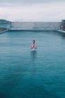 Junge Frau meditiert im Wasser eines großen Pools in der Natur — Stockfoto