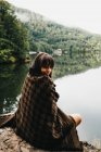 Frau sitzt mit Decke in der Nähe von See und Bergen — Stockfoto