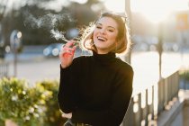 Красива жінка курить сигарету на сонячній вулиці — стокове фото