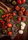 Pomodori freschi e mozzarella con foglie di basilico per insalata su superficie di legno e tovagliolo di tessuto — Foto stock