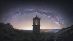Старое здание крепости в скалистой долине под ярким ночным небом с величественными звездами — стоковое фото
