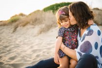 Мать целует дочь на пляже — стоковое фото
