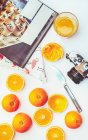 Pose plate d'oranges entières et coupées en deux avec livre de cuisine et appareil photo vintage sur table blanche — Photo de stock