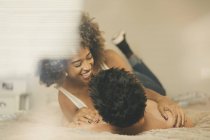 Giovane uomo e donna sdraiati sul letto e coccole in camera accogliente a casa — Foto stock