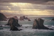 Vue pittoresque de la falaise sur un littoral calme et lisse sur fond de ciel gris — Photo de stock