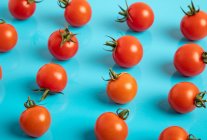 Tomates maduros frescos em espalhados no fundo azul — Fotografia de Stock