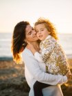 Donna di mezza età con sua figlia sulla riva del mare che sorride e si abbraccia — Foto stock