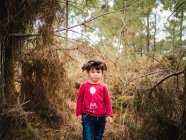 Portrait of cute little girl in red pullover standing in the middle of the forest — Stock Photo