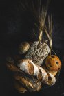 Auswahl an hausgemachten, frisch gebackenen Brotlaiben auf schwarzem Hintergrund — Stockfoto