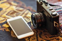 Nahaufnahme von Vintage-Kamera und Smartphone auf dekorativem Tisch — Stockfoto