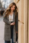 Portrait of elegant young woman leaning on wall on street — Stock Photo
