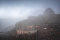 Extérieur de vieux bâtiments en briques rouges de la ville de Volterra contre le ciel brumeux, Italie — Photo de stock