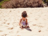 Cute little girl playing with sand at beach — Stock Photo