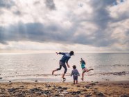 Случайный отец играл с детьми на берегу моря — стоковое фото
