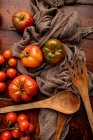 Tomates fraîches assorties et tissu sur table en bois dans la cuisine — Photo de stock