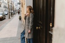 Stylische junge nachdenkliche Frau lehnt an Wand auf der Straße — Stockfoto