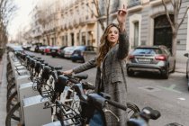 Елегантна молода леді вибирає прокат велосипеда на парковці і вказує пальцем — стокове фото