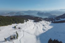 Vista panorámica de la ladera nevada con complejo en el fondo de las montañas en la bruma y la luz del sol, Suiza - foto de stock